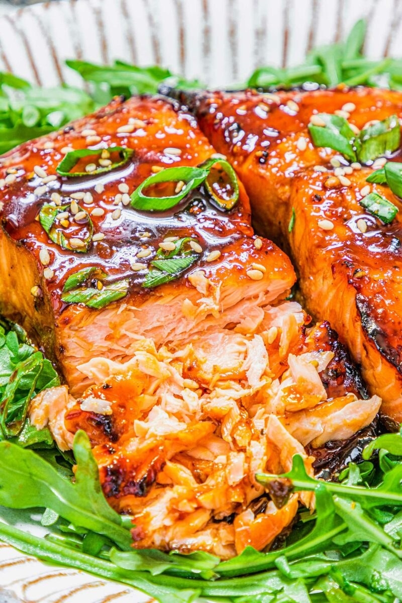 Two pieces of sesame honey salmon over arugula.